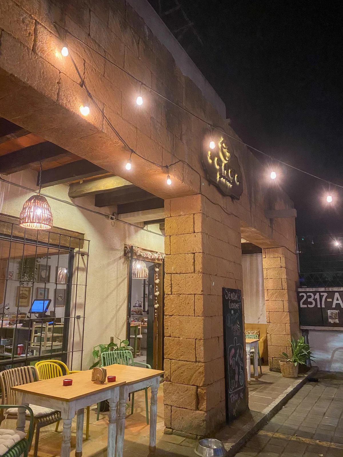 Fachada de Senda Gourmet Cafetería por la noche, con luces cálidas